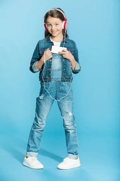 Chica en auriculares usando teléfono inteligente — Foto de Stock