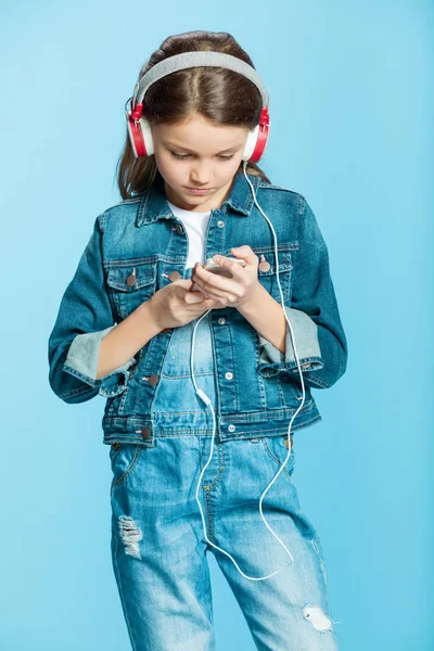 Chica en auriculares usando teléfono inteligente — Foto de Stock