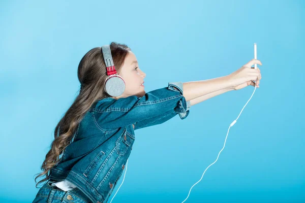 Chica en auriculares usando teléfono inteligente — Foto de Stock