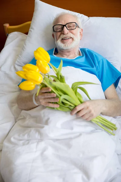 Paciente mayor con flores de tulipán — Foto de Stock