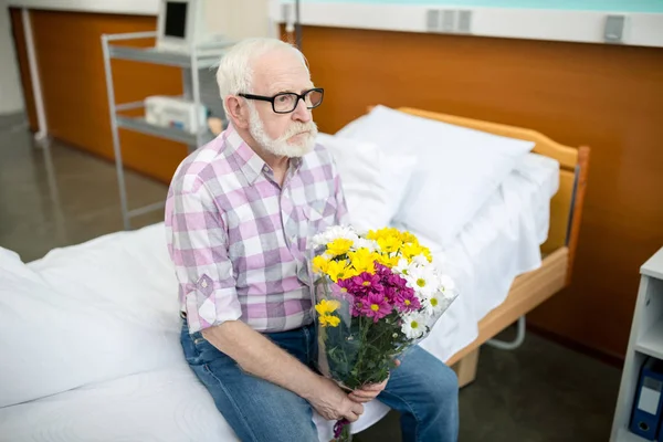 Uomo anziano con fiori in ospedale — Foto stock gratuita