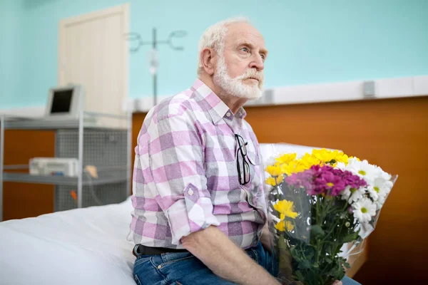 Homem sênior com flores no hospital — Fotografia de Stock Grátis