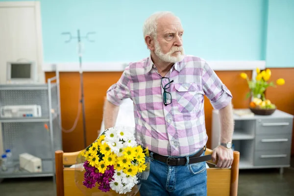 Homme âgé avec des fleurs à l'hôpital — Photo