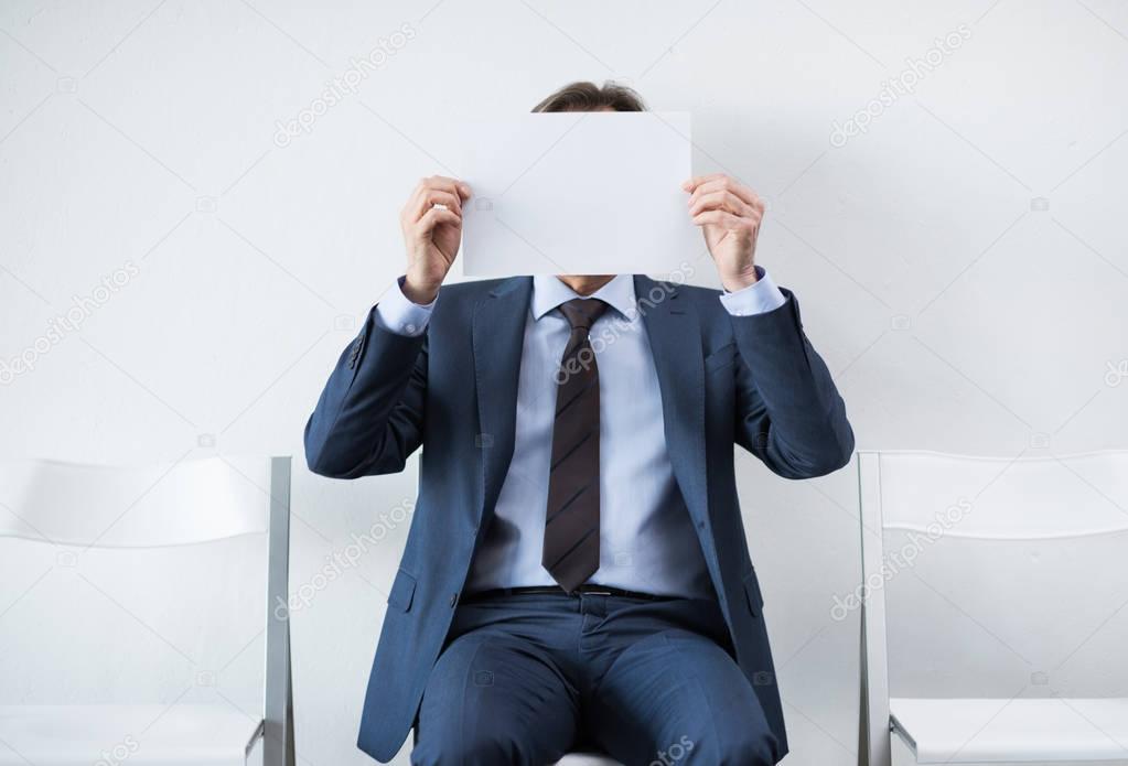 businessman covering face with paper