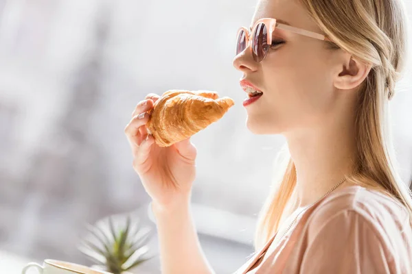 Mujer joven comiendo croissant — Foto de Stock