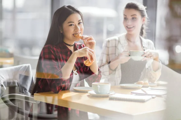 Girls eating croissants and drinking coffee — Stock Photo, Image