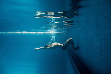 underwater picture of young swimmer in goggles exercising in swimming pool