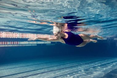 Yüzme takımı ve yüzme havuzunda eğitim gözlük içinde kadın yüzücü sualtı resim