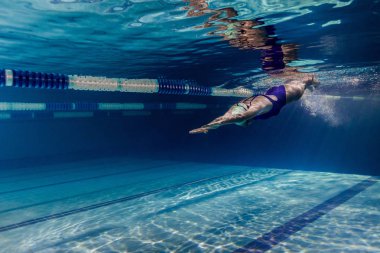 Yüzme takımı ve yüzme havuzunda eğitim gözlük içinde kadın yüzücü sualtı resim