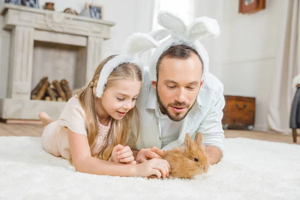 Padre e hija jugando con conejo - foto de stock