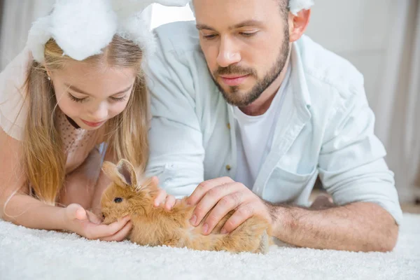 Padre e hija jugando con conejo - foto de stock