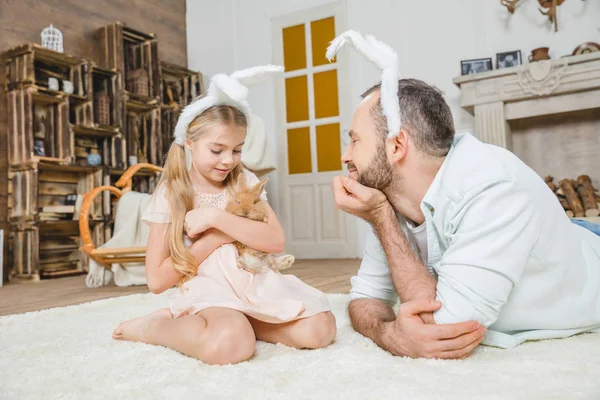 Padre e hija jugando con conejo - foto de stock