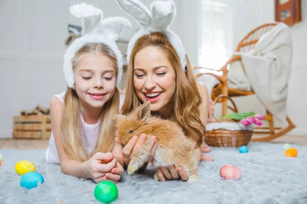 Mother and daughter playing with rabbit — Stock Photo