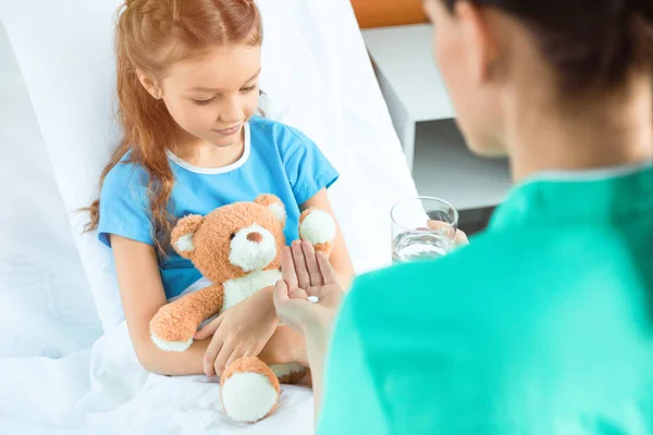 Médico dando píldora al paciente - foto de stock