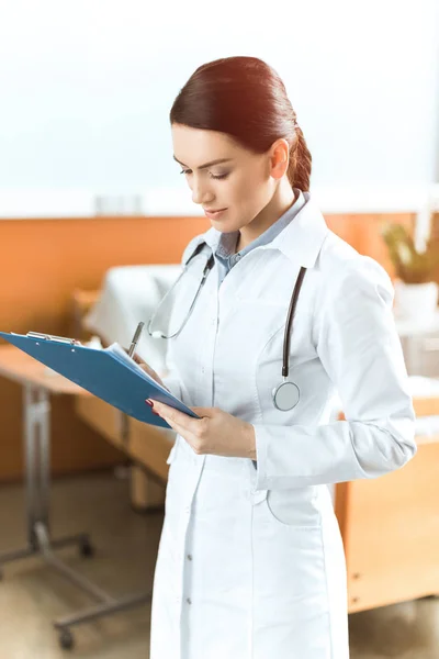 Jeune femme médecin avec presse-papiers — Photo de stock