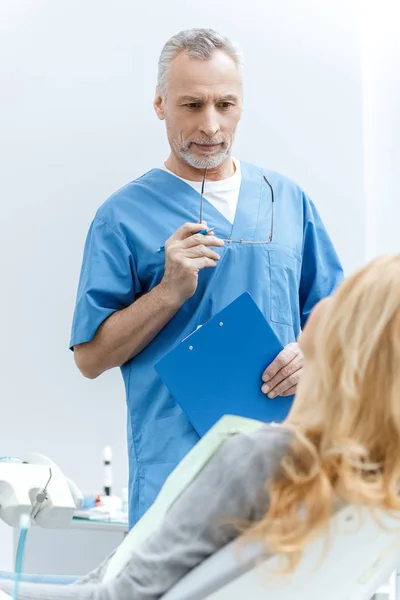 Dentista con paciente en clínica dental - foto de stock