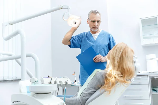 Dentista con paciente en clínica dental - foto de stock