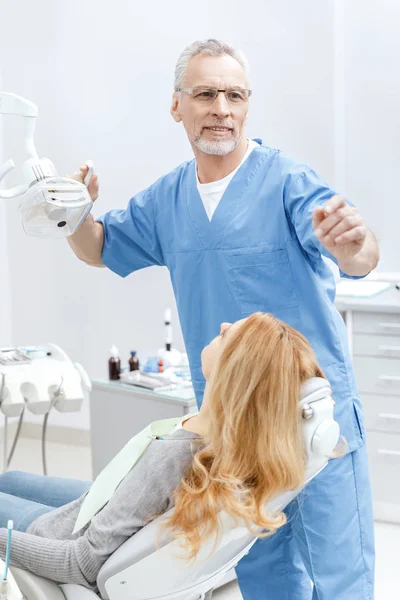 Dentista con paciente en clínica dental - foto de stock