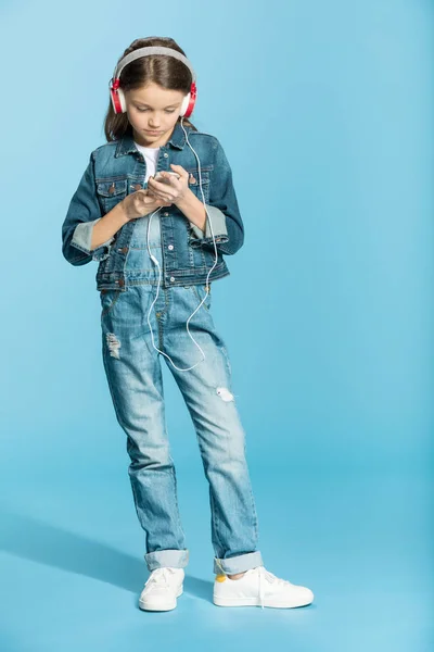 Chica en auriculares usando teléfono inteligente - foto de stock