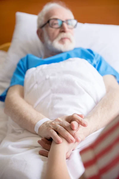 Старший пацієнт тримає руки — стокове фото
