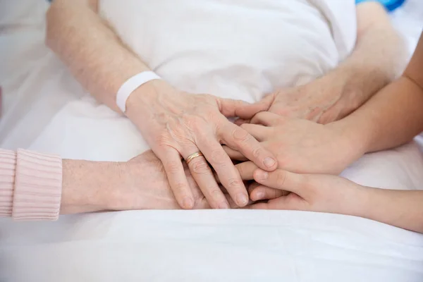 Abuela y abuelo tomados de la mano con paciente - foto de stock