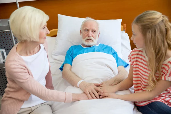 Бабушка и дедушка держатся за руки с пациентом — стоковое фото