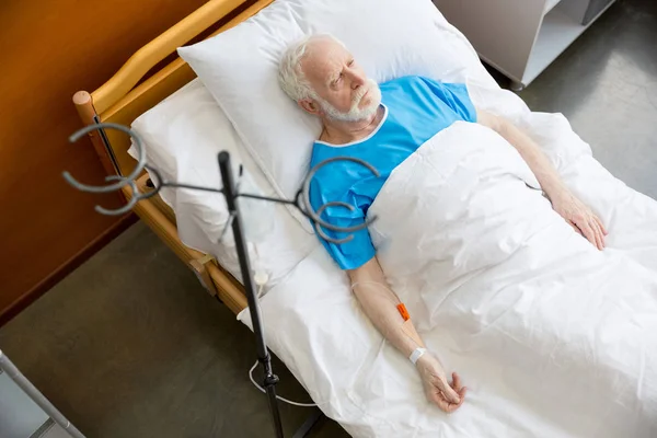 Hombre mayor en cama de hospital - foto de stock