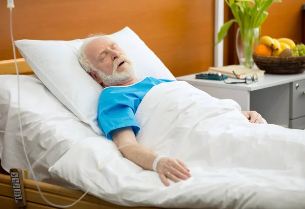 Hombre mayor en cama de hospital - foto de stock