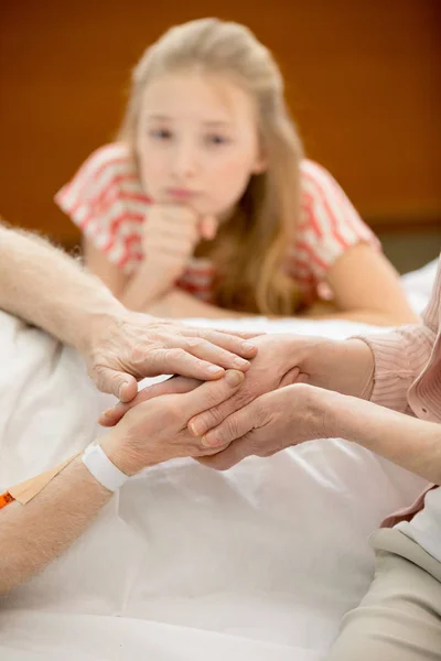 Familiares con un hombre mayor en el hospital - foto de stock