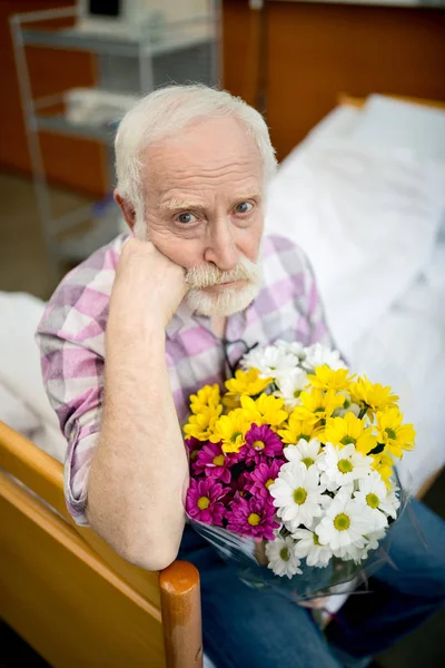 Homme âgé avec des fleurs à l'hôpital — Photo de stock