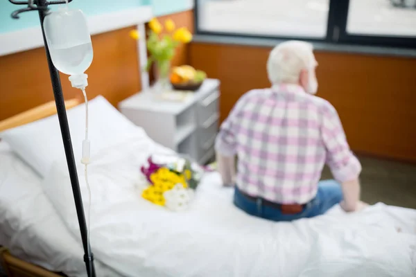 Homme âgé avec des fleurs à l'hôpital — Photo de stock