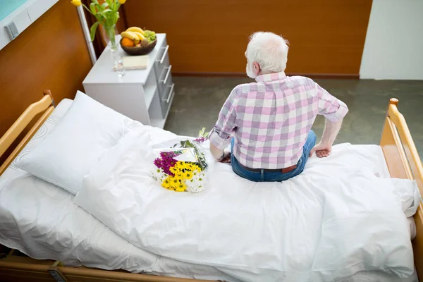 Старший мужчина с цветами в больнице — стоковое фото