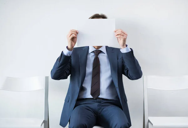 Бизнесмен, закрывающий лицо бумагой — стоковое фото