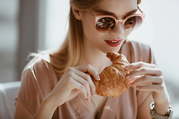 Chica con croissant en la cafetería - foto de stock