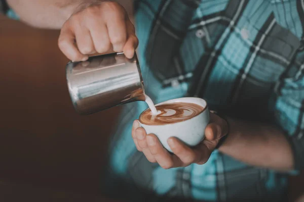 Barista vertiendo leche en el café - foto de stock