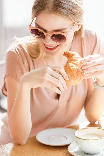 Jeune femme mangeant croissant — Photo de stock