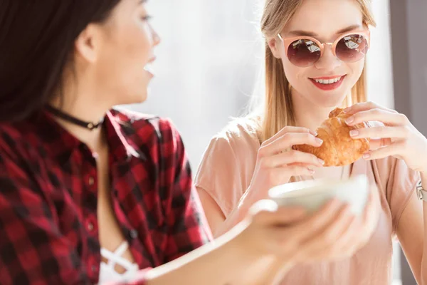 Chicas comiendo croissants y tomando café - foto de stock