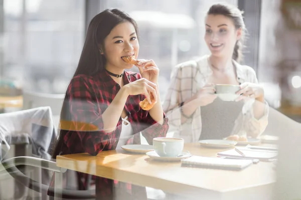 Mädchen essen Croissants und trinken Kaffee — Stockfoto