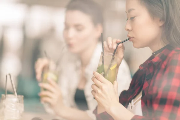 Chicas bebiendo cócteles en la cafetería - foto de stock