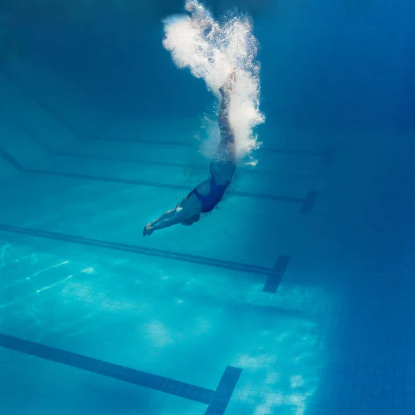 Подводная фотография молодой женщины, занимающейся плаванием в бассейне — стоковое фото