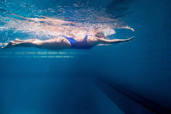 Підводне зображення молодої жінки, що плаває в басейні — стокове фото