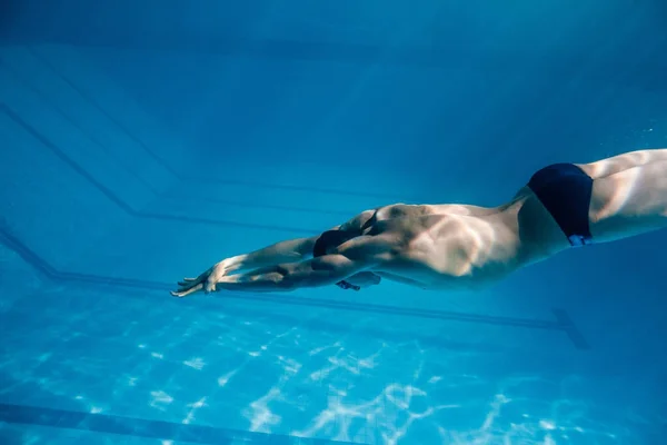 Underwater picture of young swimmer in goggles exercising in swimming pool — Stock Photo