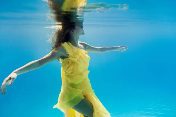 Partial view of woman in dress swimming underwater — Stock Photo