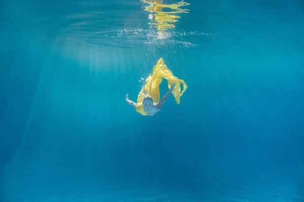 Imagem subaquática de bela jovem no vestido nadando na piscina — Fotografia de Stock