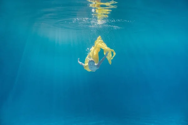 Unterwasserbild der schönen jungen Frau im Kleid, die im Schwimmbad schwimmt — Stockfoto