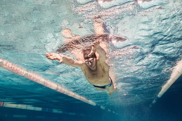Unterwasserbild junger Schwimmer mit Schirmmütze und Schutzbrille beim Training im Schwimmbad — Stockfoto