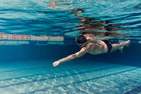 Photo sous-marine de jeune nageur en casquette et lunettes de formation dans la piscine — Stock Photo