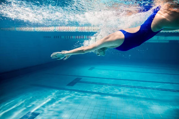 Подводная фотография молодой женщины, занимающейся плаванием в бассейне — стоковое фото