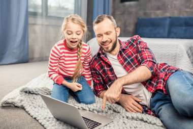 Baba ve kızı dizüstü bilgisayar kullanıyor. 