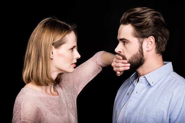Woman covers mouth of man